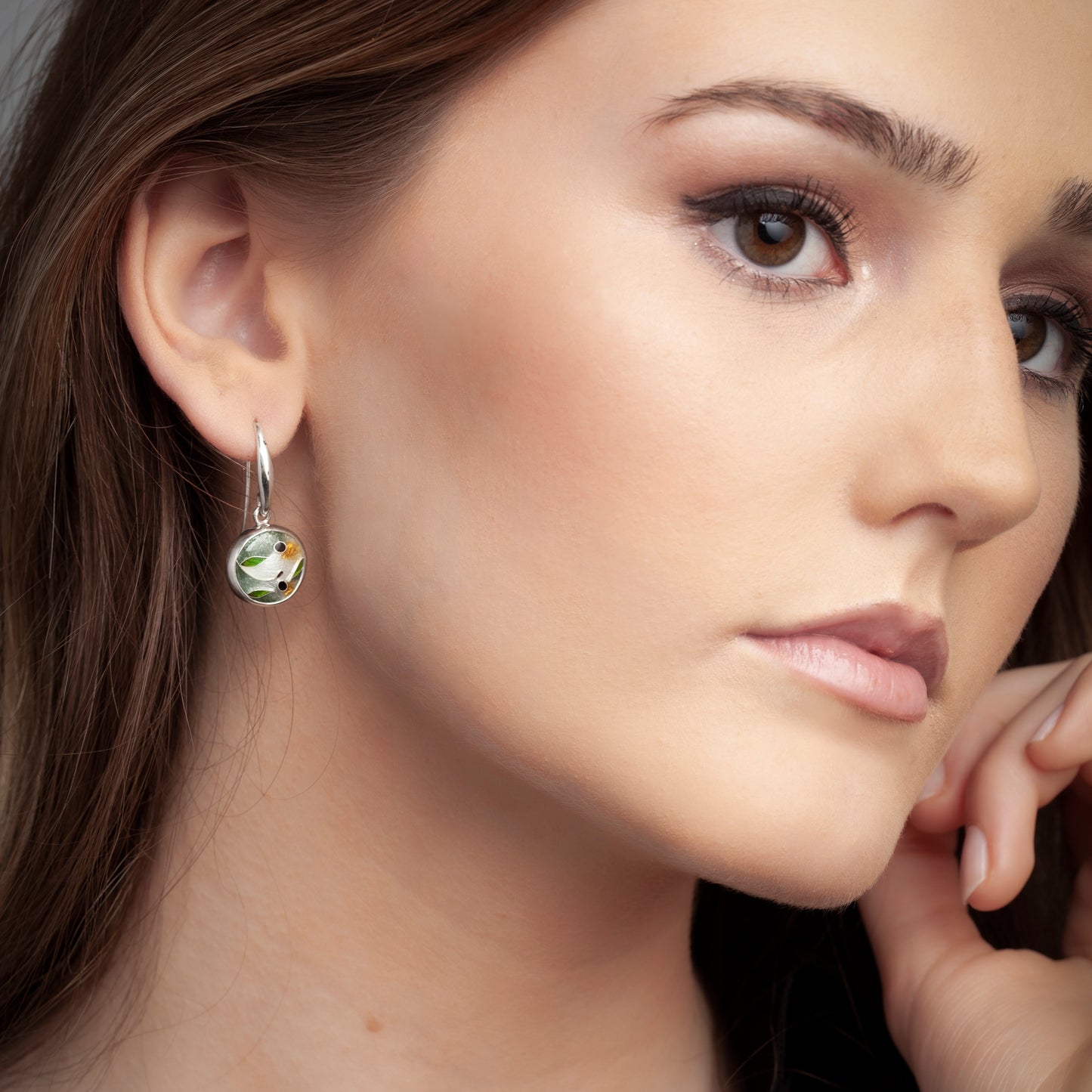 Close-up of a woman wearing a green gemstone earring.