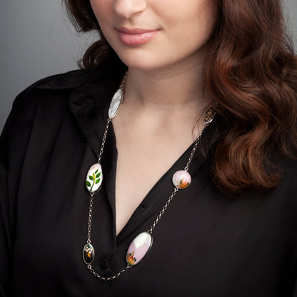 Woman wearing a black blouse and a necklace with colorful pendants against a gray background