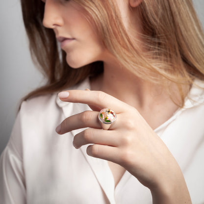 Woman wearing a ring with a green gemstone on a plain background