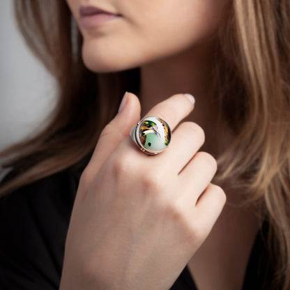 Woman wearing a ring with a green gemstone on a neutral background